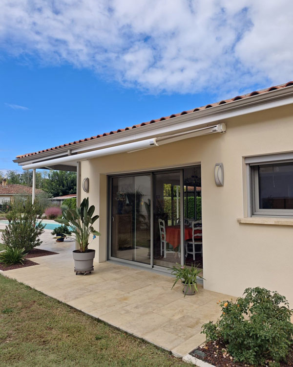Store banne avec toile beige installé sur une terrasse au bord d’une piscine à Mazerolles