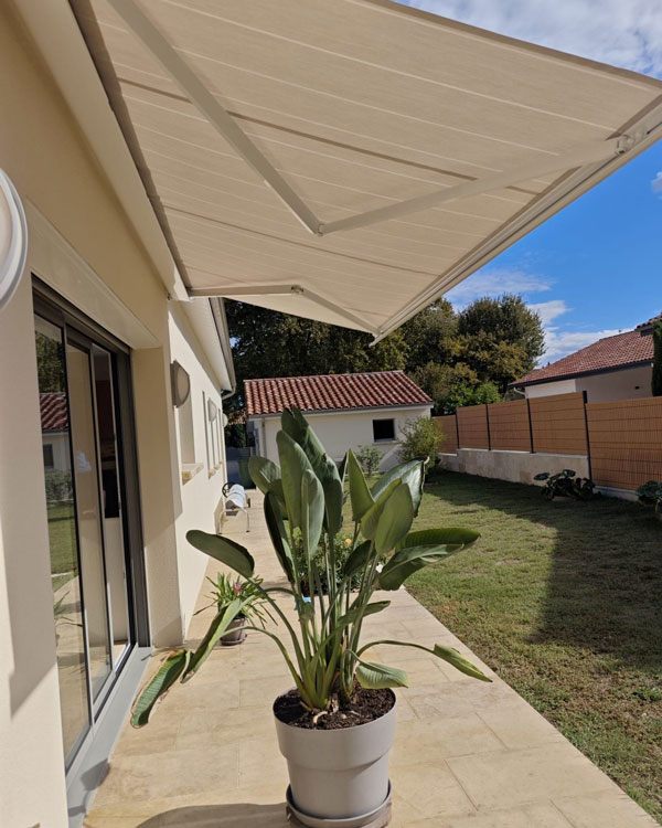 Store banne avec toile beige installé sur une terrasse au bord d’une piscine à Mazerolles